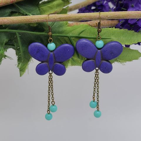 Handmade purple butterfly dangle earrings with red bead accents and antique brass chain drops – boho insect-inspired jewelry for women