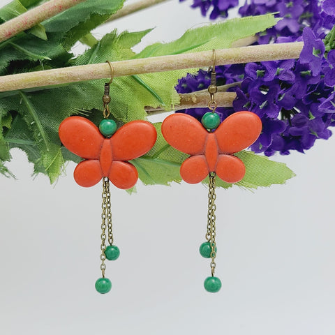 Handmade red butterfly dangle earrings with red bead accents and antique brass chain drops – boho insect-inspired jewelry for women